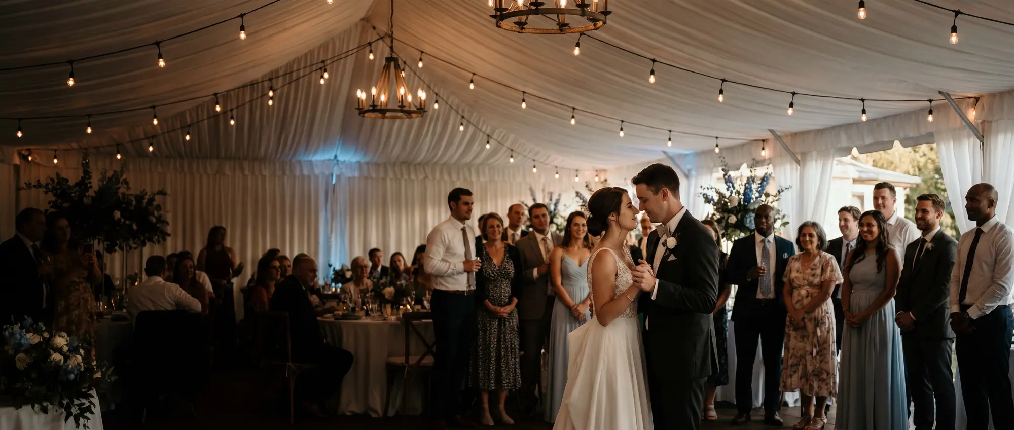 A couple's first dance under string lights, surrounded by guests