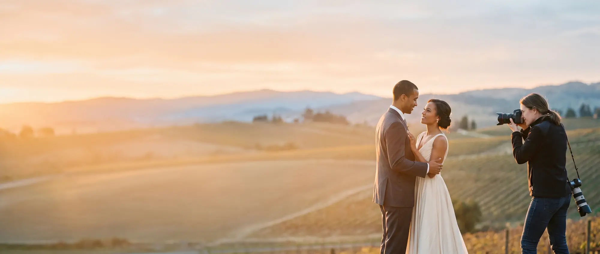 A photographer shooting a wedding couple outside a beautiful banquet hall